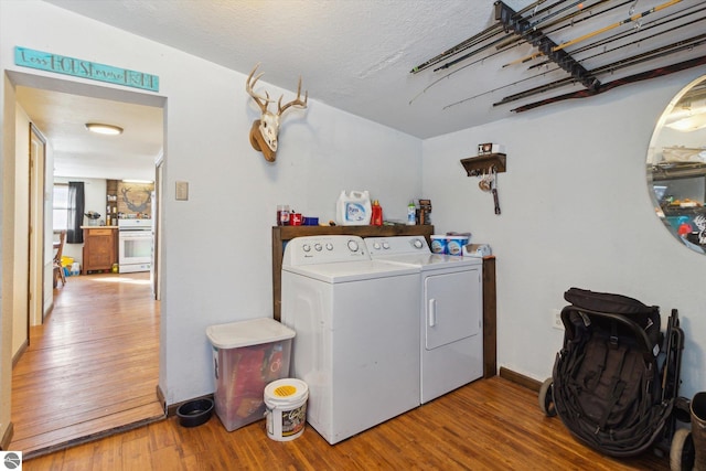 laundry area featuring laundry area, a textured ceiling, wood finished floors, and washing machine and clothes dryer