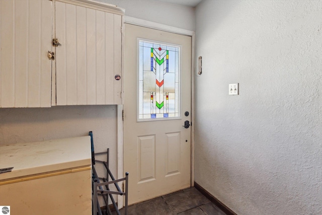 entryway featuring a textured wall and baseboards