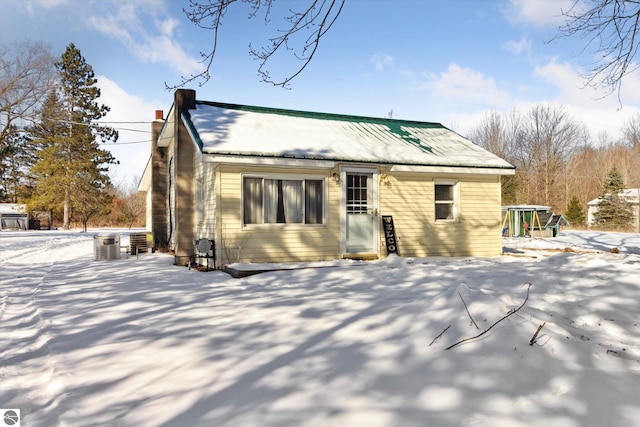 snow covered house featuring central AC and a chimney