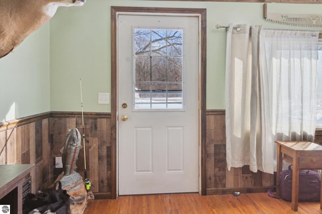 entryway with a wealth of natural light, a wainscoted wall, and wood finished floors