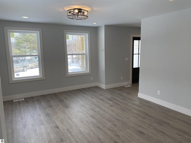 unfurnished room featuring a wealth of natural light, visible vents, and baseboards