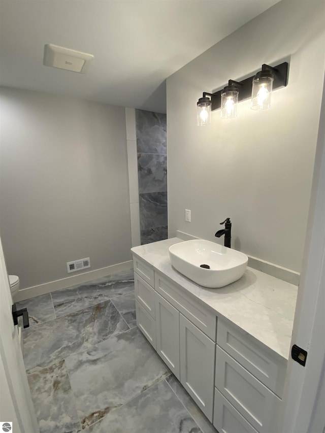 full bathroom featuring toilet, vanity, visible vents, baseboards, and marble finish floor