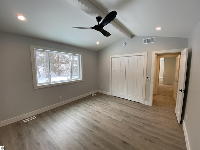 unfurnished bedroom with vaulted ceiling with beams, baseboards, visible vents, and wood finished floors