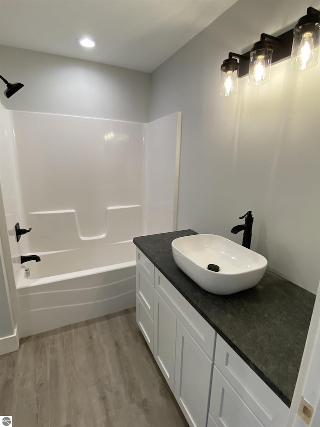 full bath with tub / shower combination, wood finished floors, and vanity