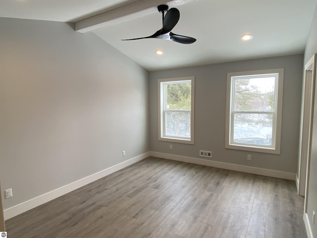 unfurnished room featuring vaulted ceiling with beams, wood finished floors, a ceiling fan, visible vents, and baseboards