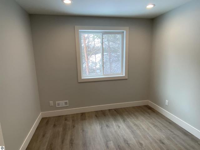 unfurnished room with light wood-style floors, baseboards, visible vents, and recessed lighting