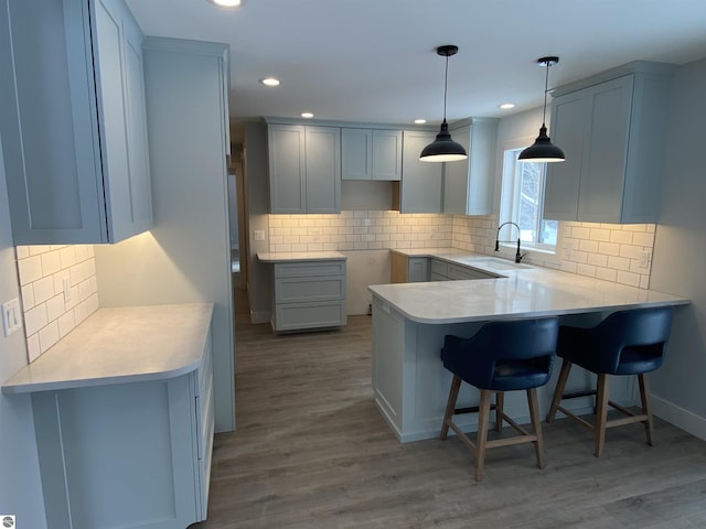 kitchen featuring a kitchen bar, light countertops, a sink, and wood finished floors