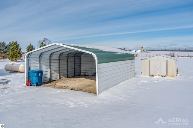 snow covered structure with a storage shed and a detached carport