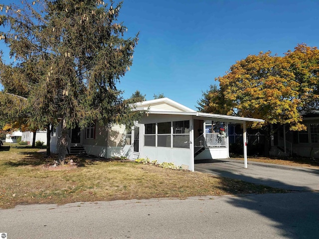 view of front of home with a carport, a front yard, and a sunroom