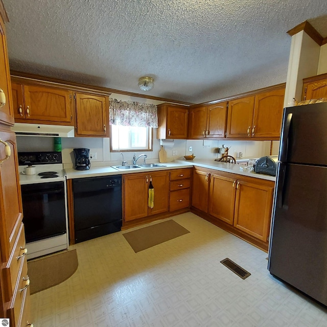 kitchen featuring light floors, brown cabinetry, a sink, and black appliances