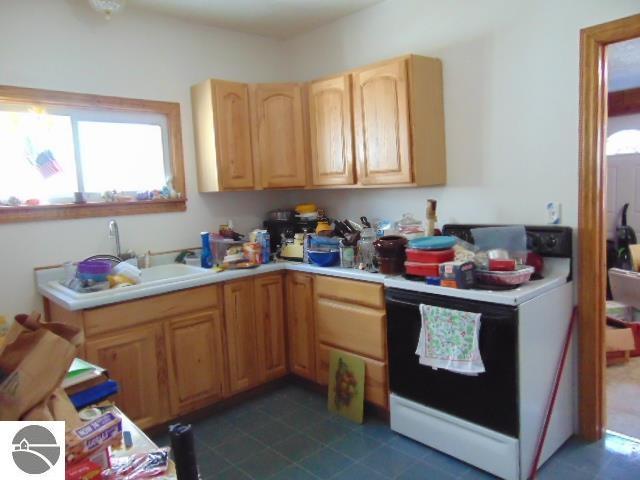 kitchen featuring light countertops, a sink, and white electric range oven