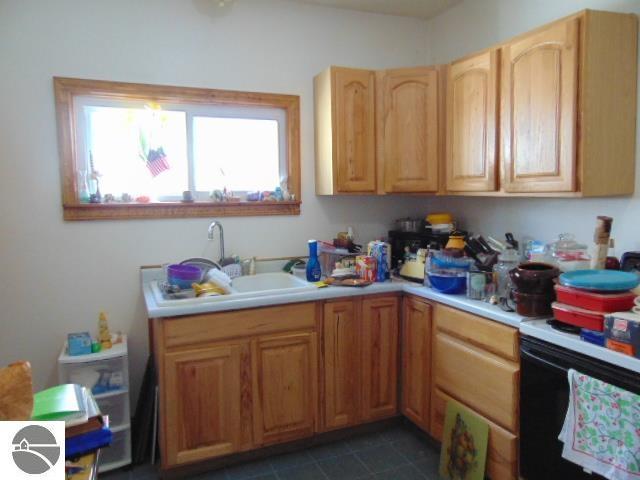 kitchen featuring range with electric cooktop, light countertops, a sink, and dark tile patterned flooring