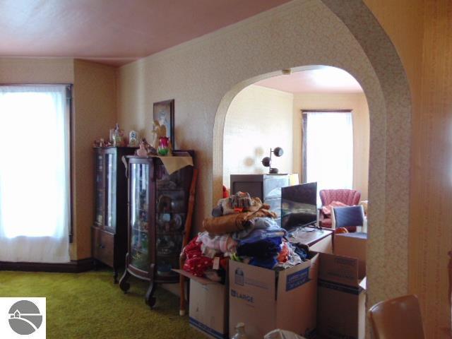 home office with arched walkways, plenty of natural light, and carpet