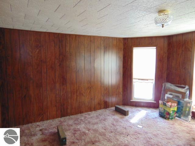 empty room with wooden walls and carpet flooring