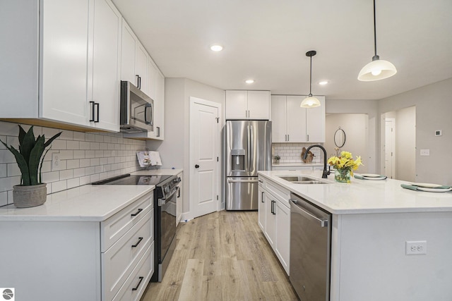 kitchen featuring stainless steel appliances, a sink, white cabinets, light countertops, and pendant lighting