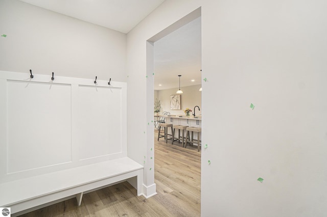 mudroom with light wood-type flooring and a sink