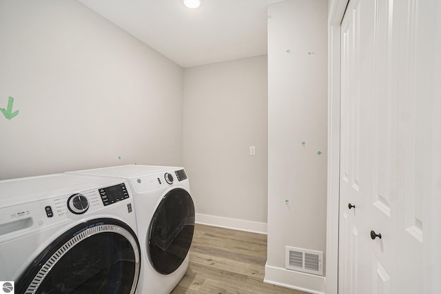 laundry room featuring washer and dryer, visible vents, light wood-type flooring, laundry area, and baseboards