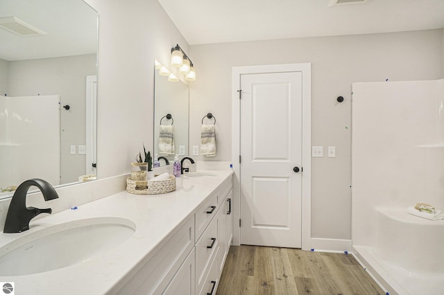 bathroom with double vanity, visible vents, a sink, and wood finished floors