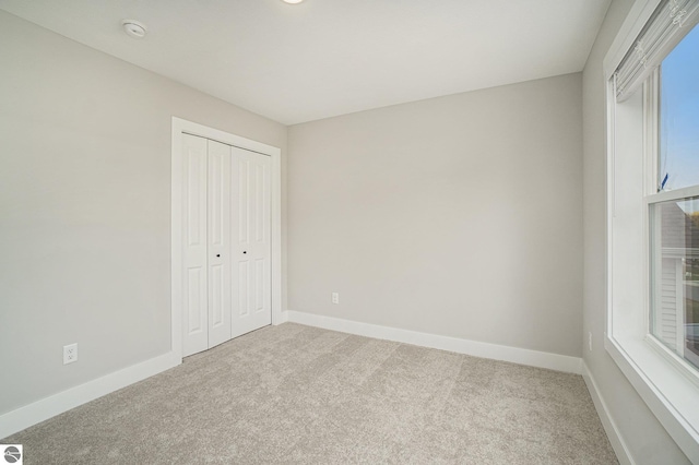 unfurnished bedroom with carpet floors, baseboards, and a closet