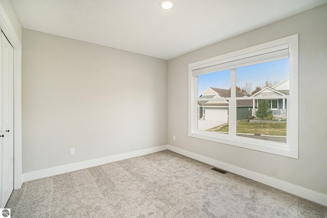 unfurnished room featuring light colored carpet, visible vents, and baseboards