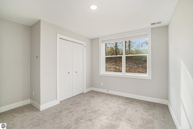 unfurnished bedroom with light colored carpet, a closet, visible vents, and baseboards