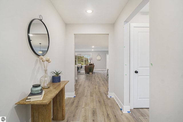 hallway with light wood-type flooring and baseboards