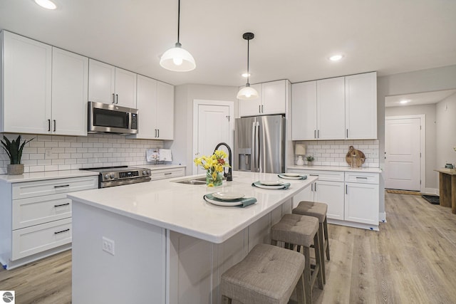 kitchen with light countertops, appliances with stainless steel finishes, a sink, and white cabinets