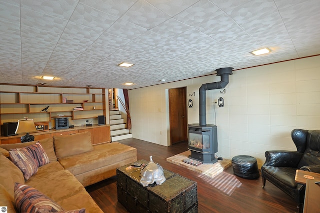 living room with a wood stove, stairs, tile walls, and dark wood-style flooring