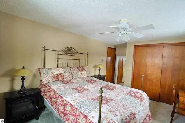 carpeted bedroom with a ceiling fan, a closet, and a textured ceiling