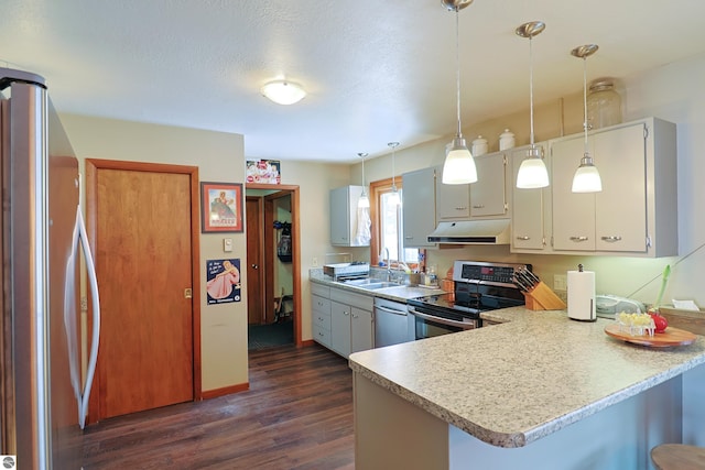 kitchen with light countertops, hanging light fixtures, appliances with stainless steel finishes, a peninsula, and under cabinet range hood