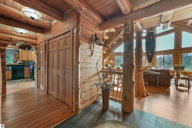 hall with arched walkways, wooden ceiling, wood finished floors, beamed ceiling, and rustic walls