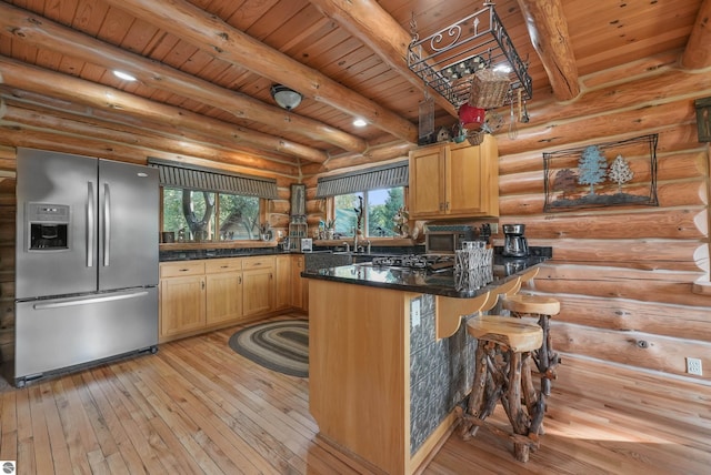 kitchen featuring a breakfast bar area, a peninsula, a healthy amount of sunlight, stainless steel refrigerator with ice dispenser, and light wood finished floors