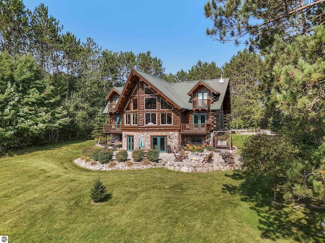 rear view of house with stone siding, a yard, log siding, and a wooden deck