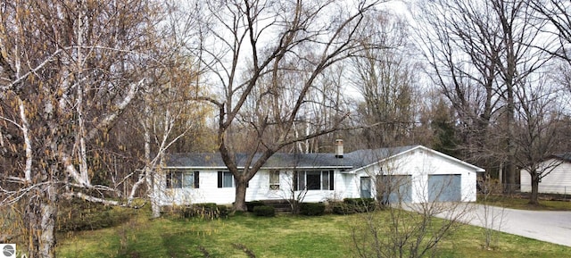 ranch-style house with a garage, concrete driveway, and a front lawn