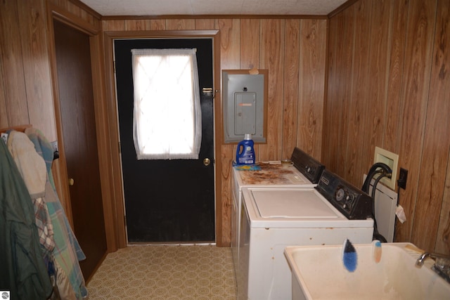 washroom with a sink, wood walls, separate washer and dryer, laundry area, and electric panel