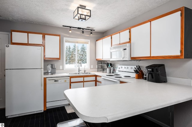 kitchen featuring light countertops, white cabinets, a sink, white appliances, and a peninsula