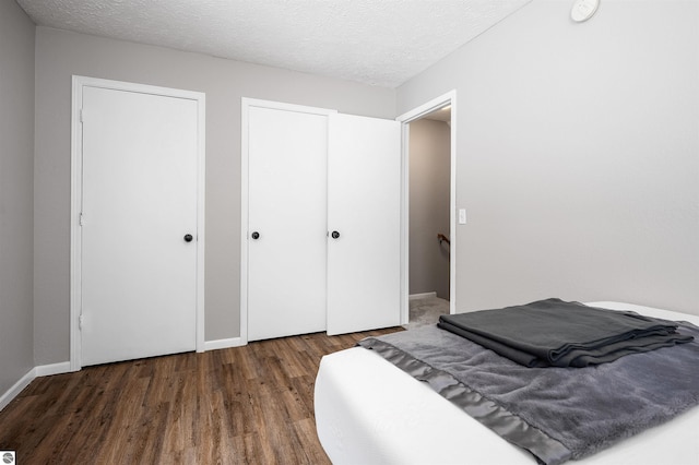 bedroom featuring dark wood-style flooring, a textured ceiling, and baseboards