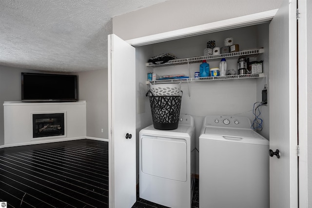 laundry area featuring a glass covered fireplace, a textured ceiling, separate washer and dryer, wood finished floors, and laundry area