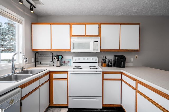 kitchen featuring a textured ceiling, white appliances, a sink, white cabinets, and light countertops