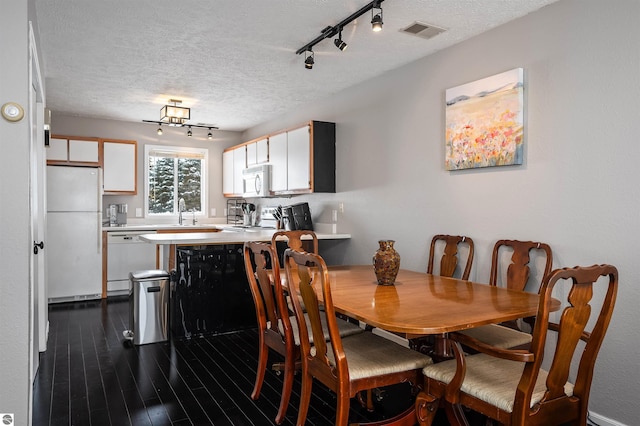 dining room featuring visible vents, dark wood finished floors, and a textured ceiling