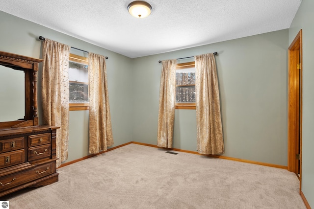 unfurnished bedroom featuring baseboards, a textured ceiling, visible vents, and carpet flooring