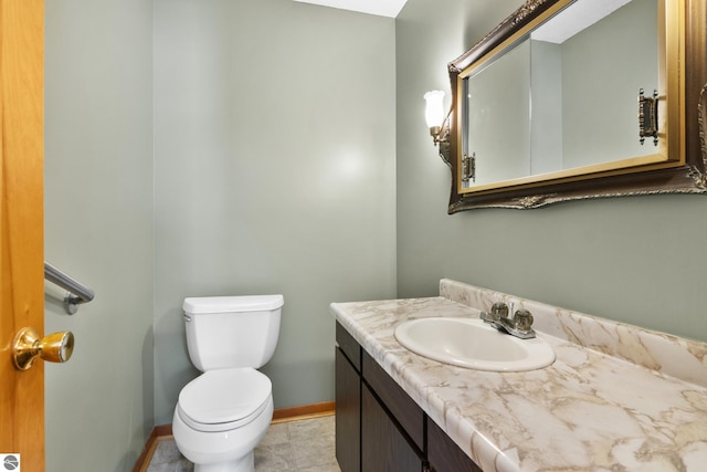 half bathroom with baseboards, vanity, and toilet