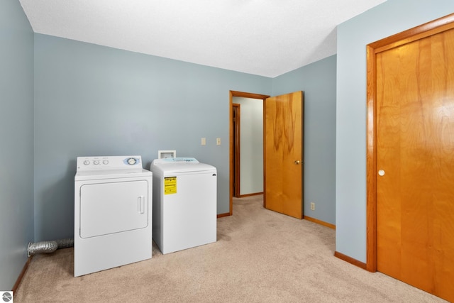 clothes washing area with laundry area, light colored carpet, baseboards, and separate washer and dryer