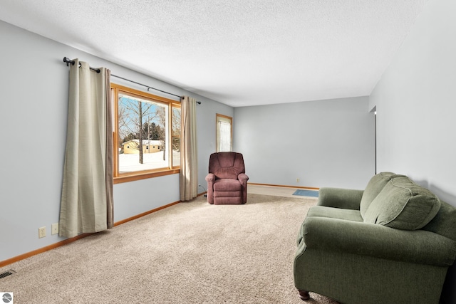 living area with visible vents, a textured ceiling, baseboards, and carpet flooring