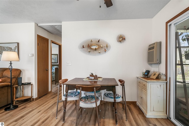 dining room with light wood-style floors, a healthy amount of sunlight, and a textured ceiling