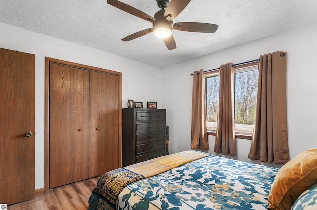 bedroom featuring light wood finished floors, a closet, a ceiling fan, and a textured ceiling