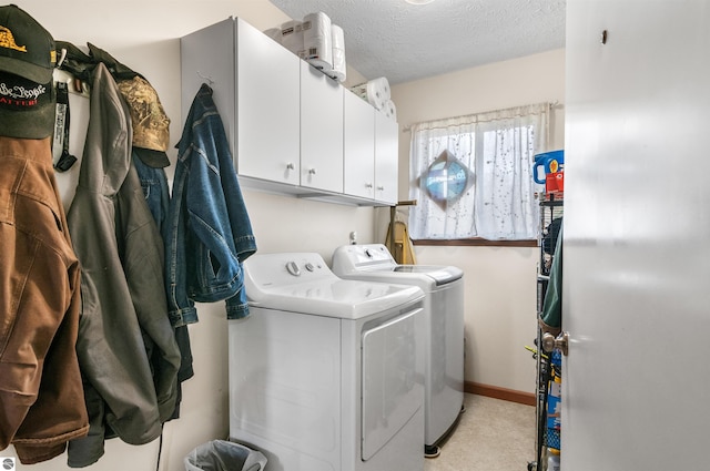 laundry room with a textured ceiling, separate washer and dryer, cabinet space, and baseboards