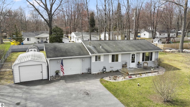 ranch-style home with a residential view, aphalt driveway, an attached garage, fence, and a front lawn