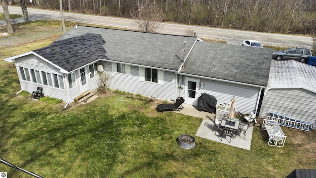 back of house featuring a yard, an outdoor fire pit, a patio, and a shingled roof