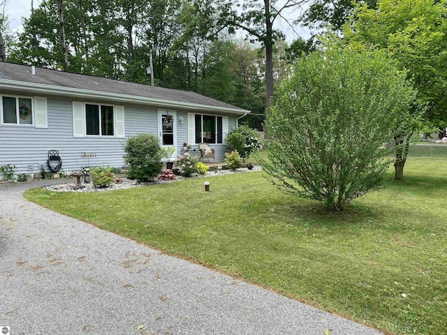 ranch-style house featuring a front yard and gravel driveway